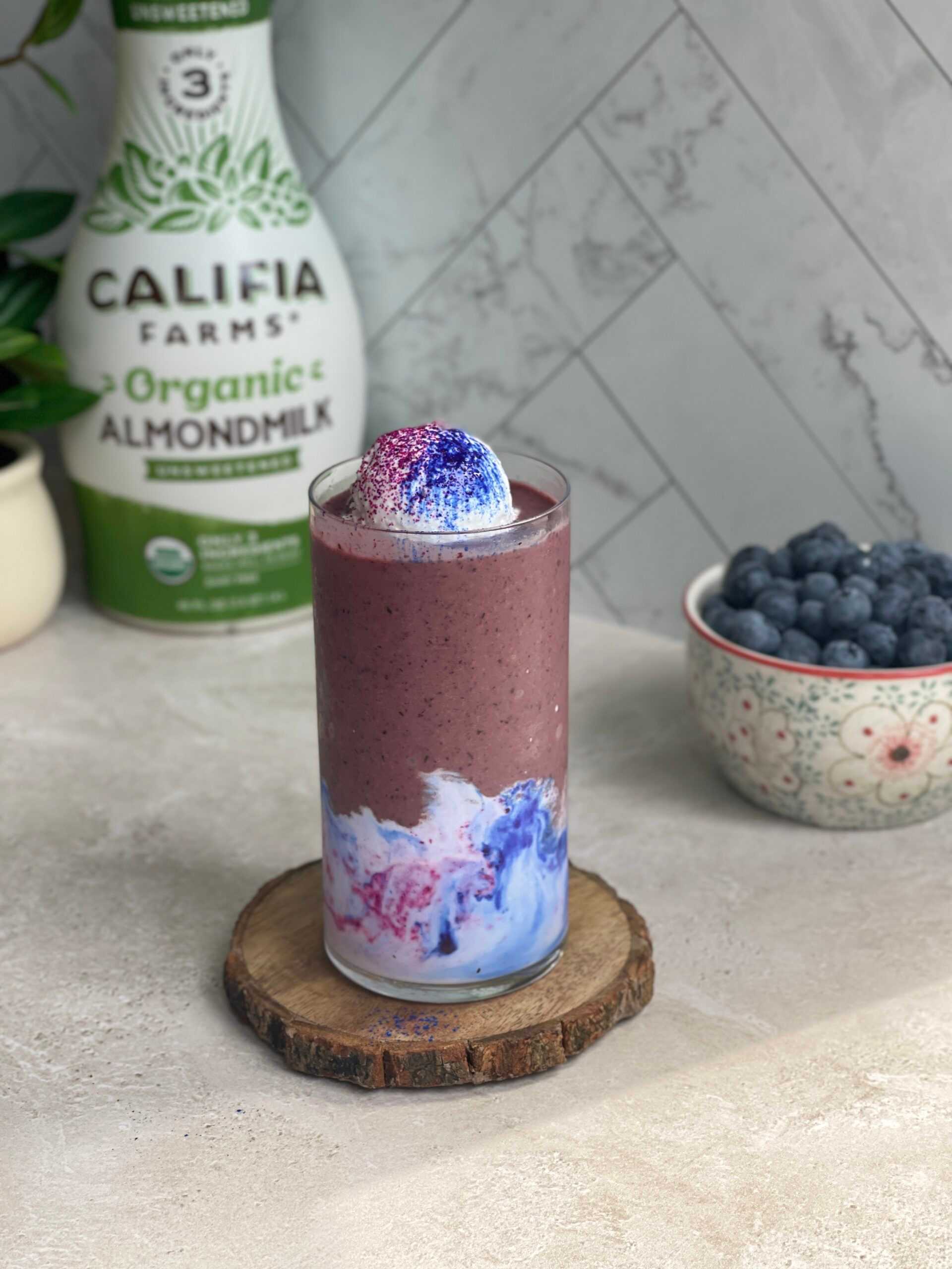 A purple smoothie sits at the center of the image, with Califia Farms Organic Almondmilk in the background.