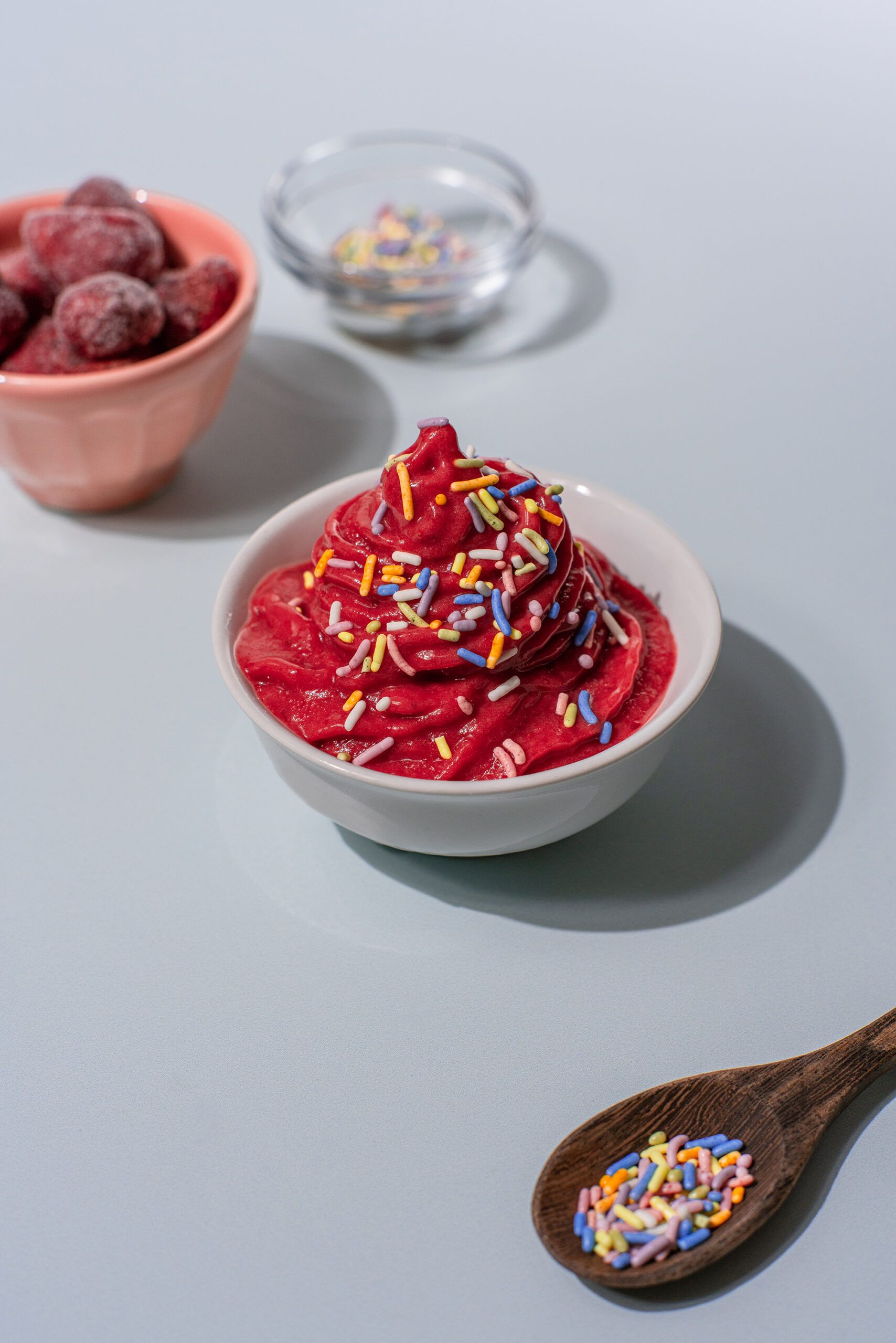 A bowl of strawberry soft serve with rainbow sprinkles sits at the center of the image.