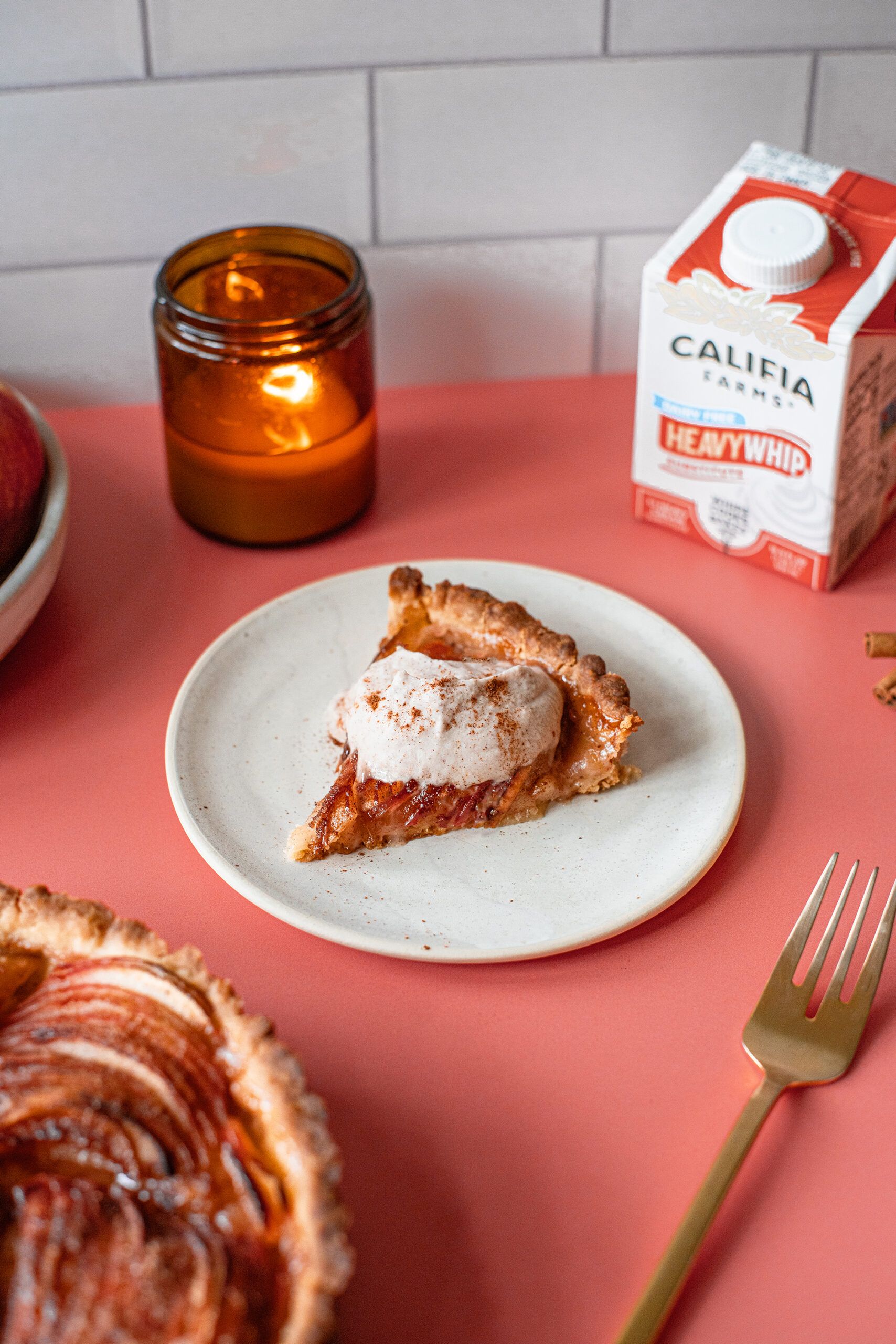 A slice of apple tart sits in the foreground of the image, with Califia Farms Heavy Whip behind.