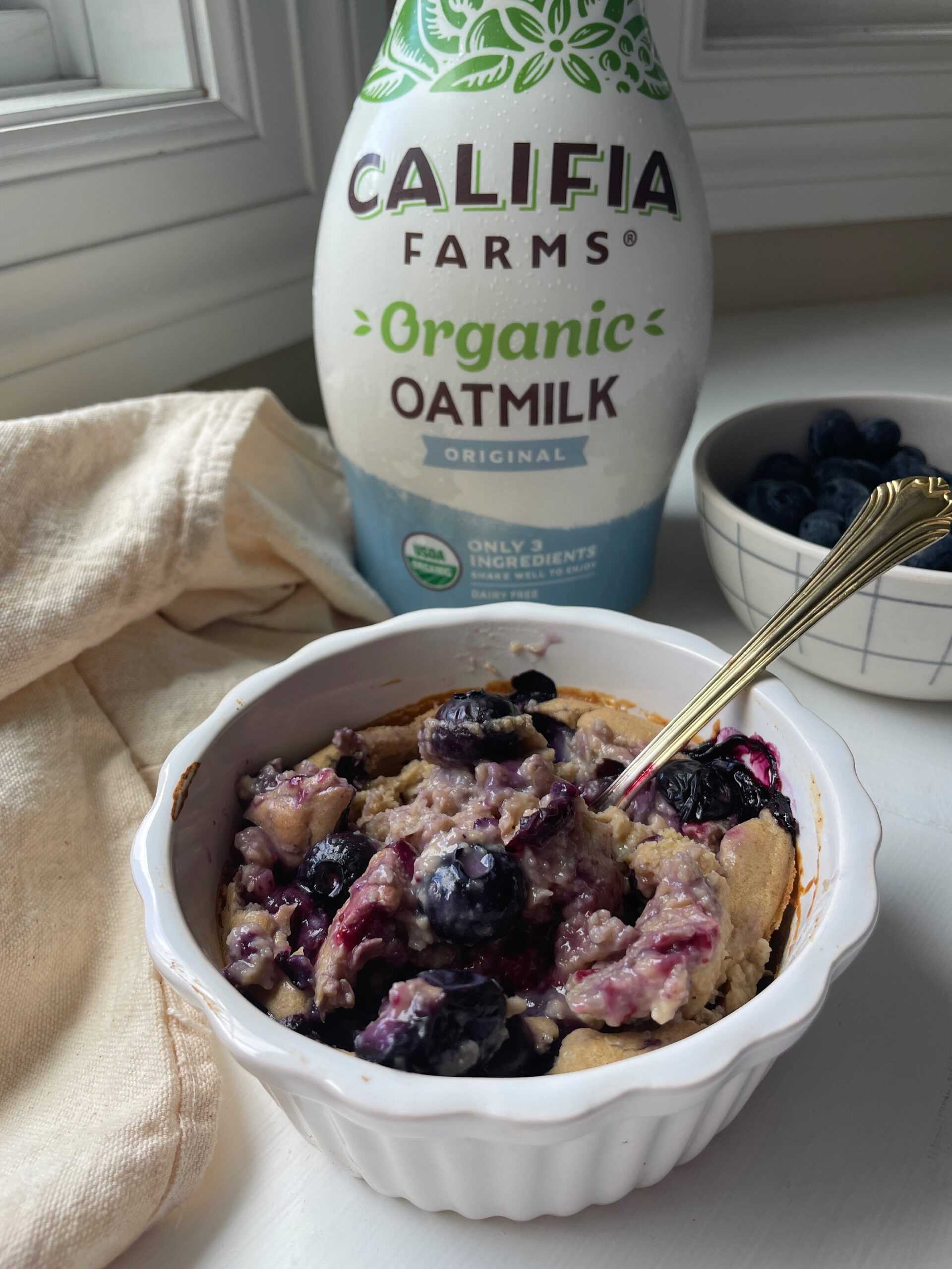 Blueberry baked oatmeal sits in the foreground of the image, with Califia Farms Organic Oatmilk behind.