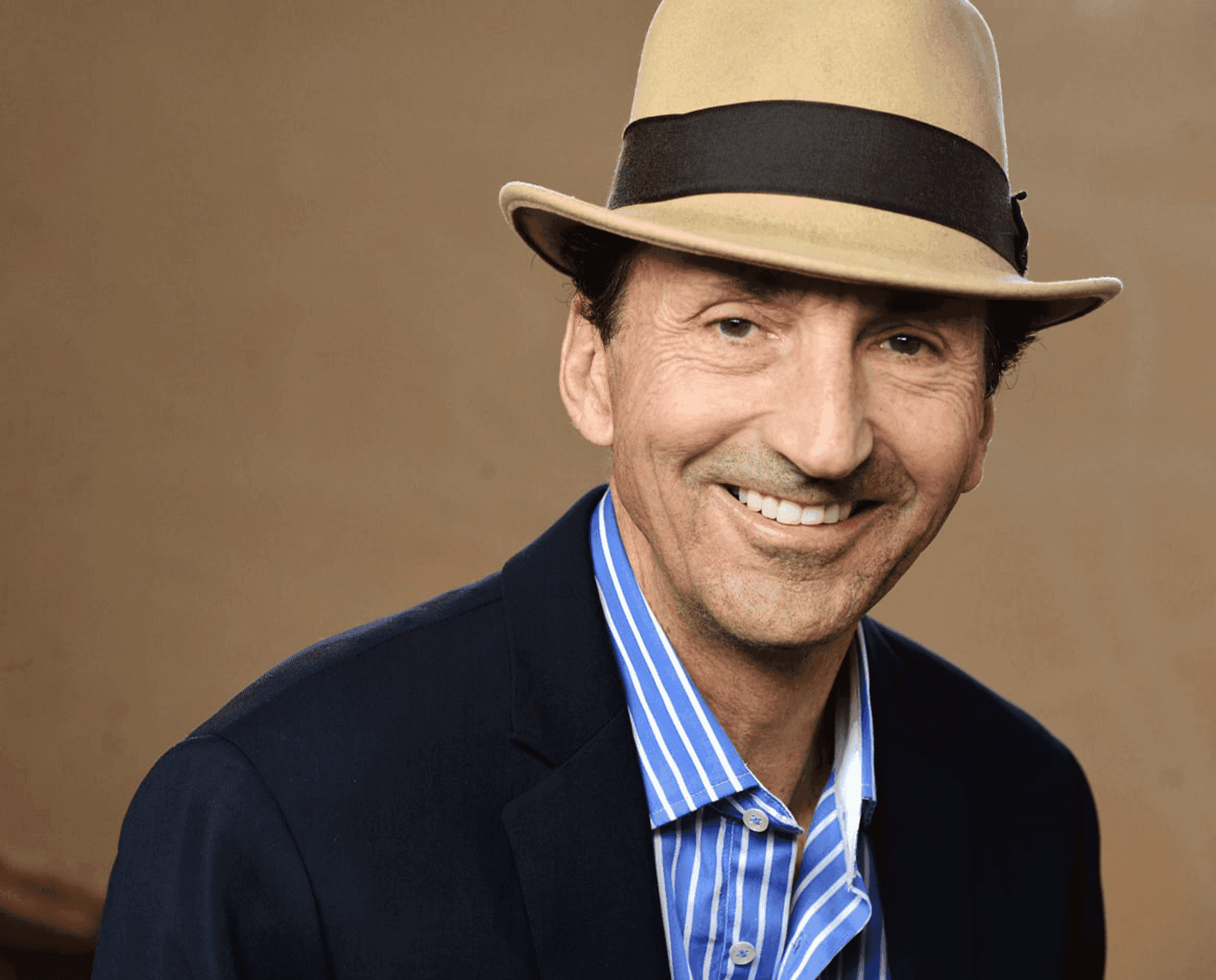 close-up of photo of Greg wearing a suit and hat with a brown background