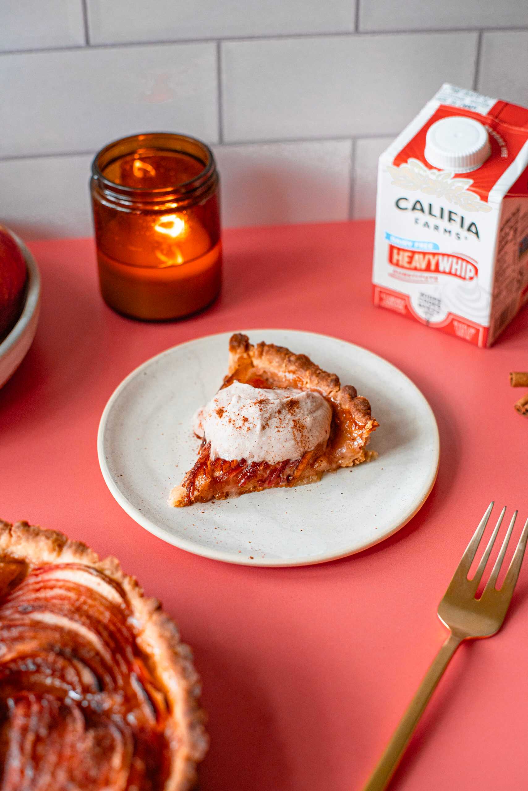 A slice of apple tart sits in the foreground of the image, with Califia Farms Heavy Whip behind.