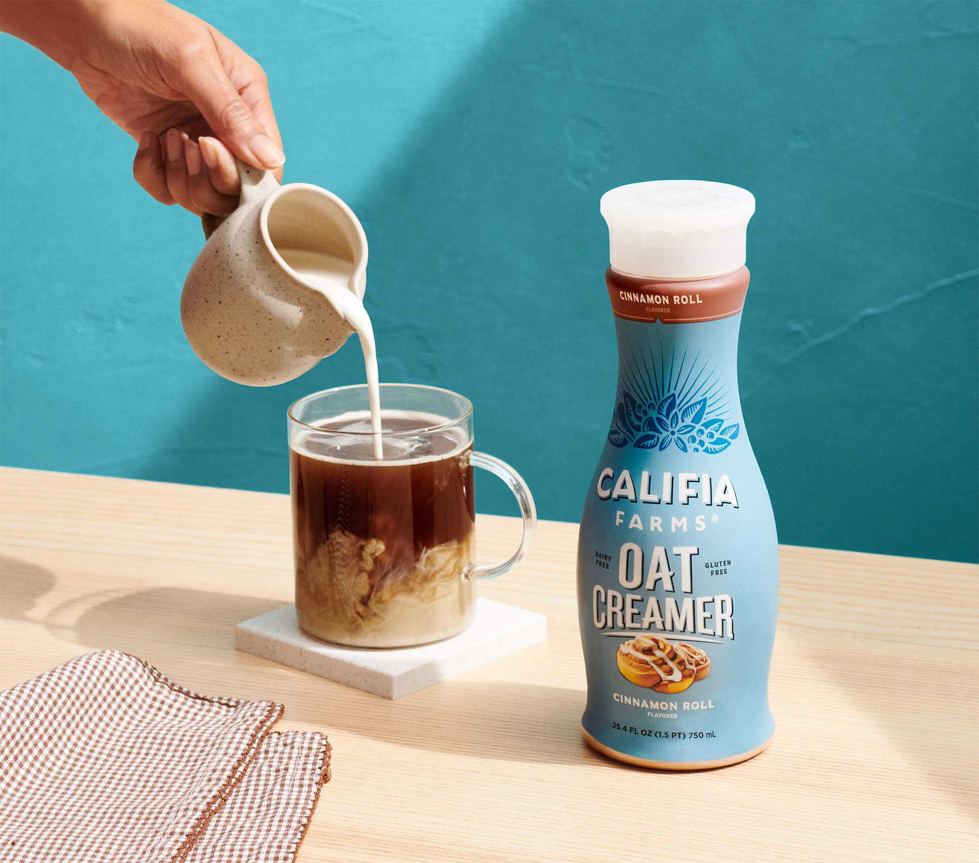 close-up of oat creamer being poured into coffee with Califia Oat Creamer in the background